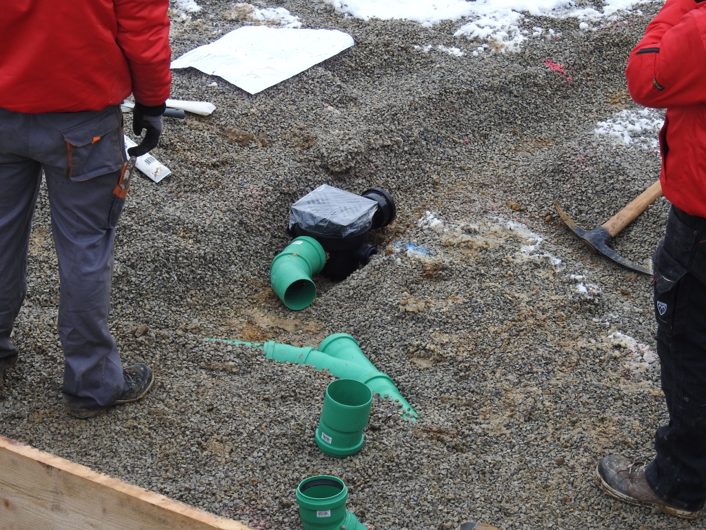 Bodenabfluss und Abflussrohre sind in einem Graben in der Baugrube platziert.